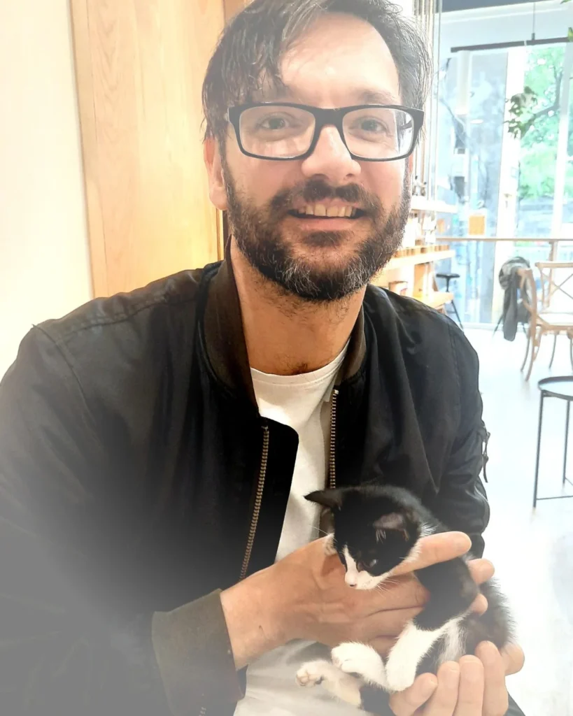Arnold, founder and editor of Catcredo, holding a black-and-white kitten